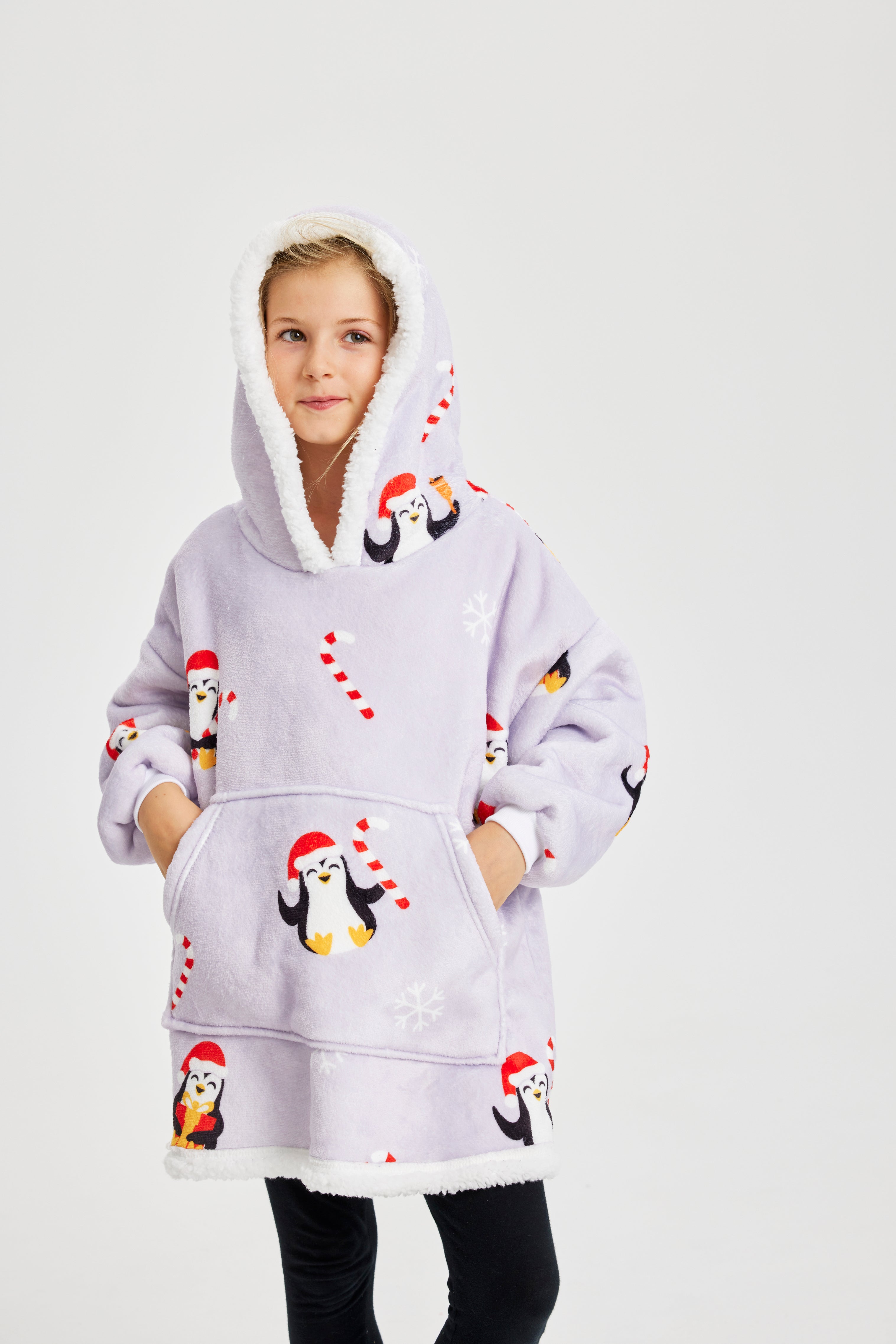 Een lachend kind dat een lichtpaarse kerst hoodie met pinguïns draagt.